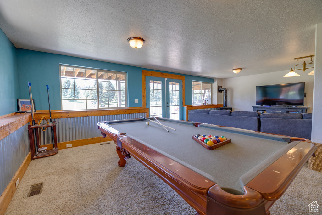 Recreation room featuring a textured ceiling, pool table, a wainscoted wall, carpet, and wooden walls