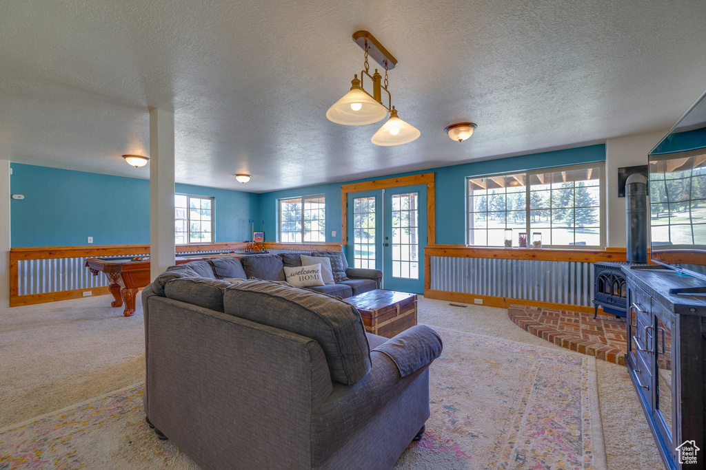 Living area featuring a wood stove, a textured ceiling, carpet flooring, french doors, and billiards