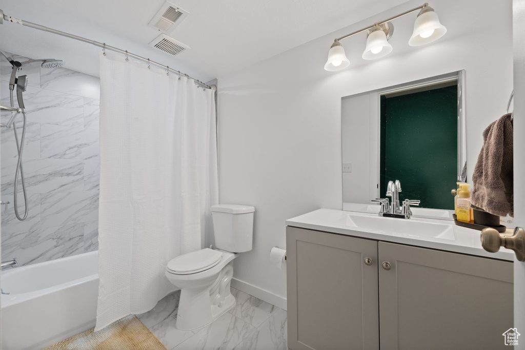 Full bathroom featuring marble finish flooring, vanity, and shower / bath combo with shower curtain