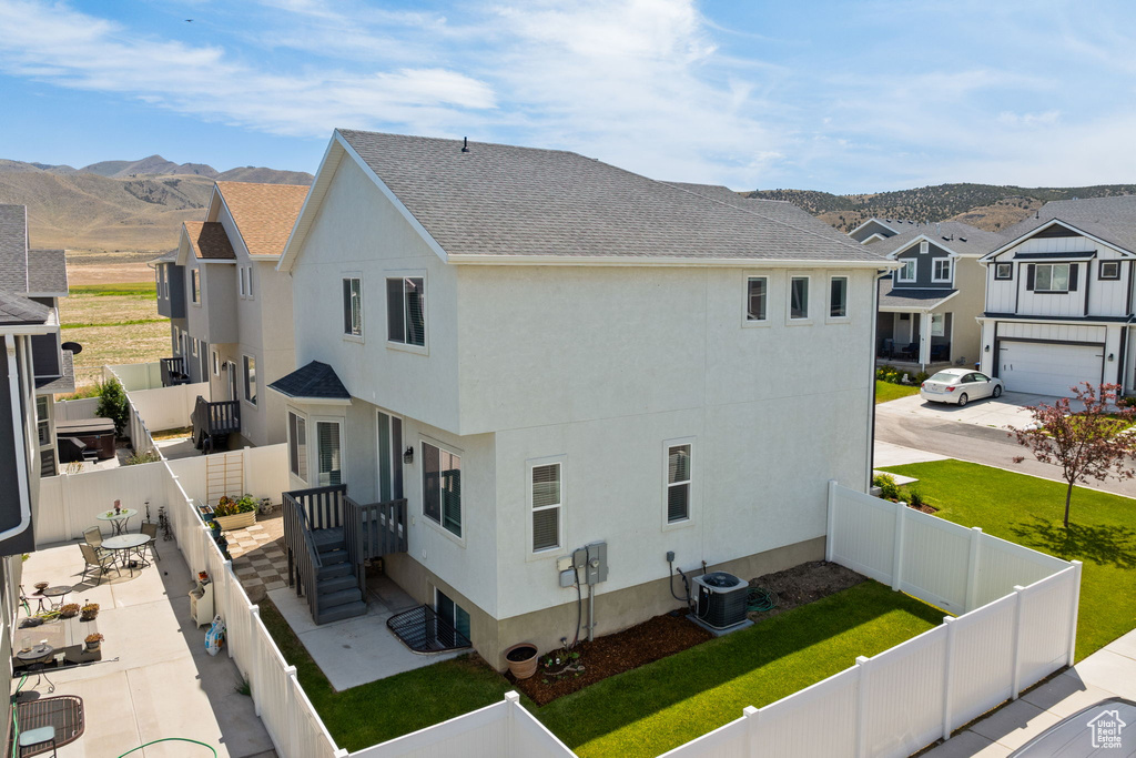View of side of home with stucco siding, roof with shingles, a fenced backyard, and a mountain view