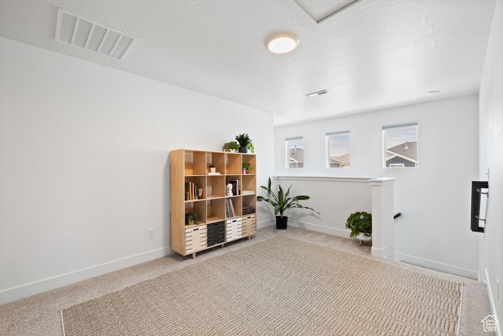 Unfurnished room featuring carpet flooring and an upstairs landing