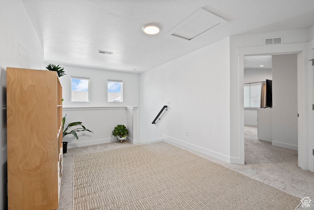 Carpeted empty room featuring attic access and baseboards