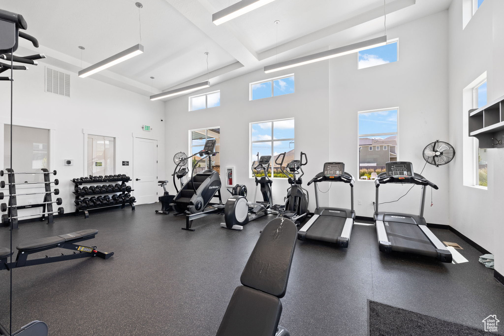 Exercise room featuring a high ceiling, plenty of natural light, and beamed ceiling