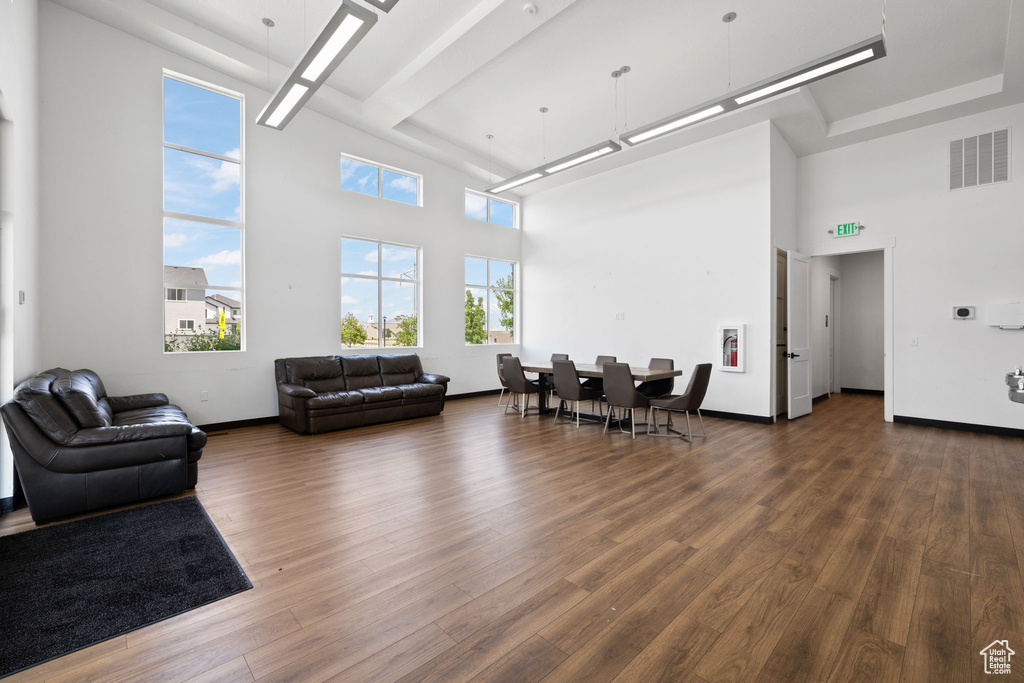 Living room featuring a high ceiling and dark wood-style flooring