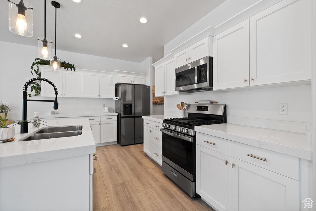 Kitchen featuring stainless steel appliances, recessed lighting, white cabinetry, light wood-style floors, and pendant lighting