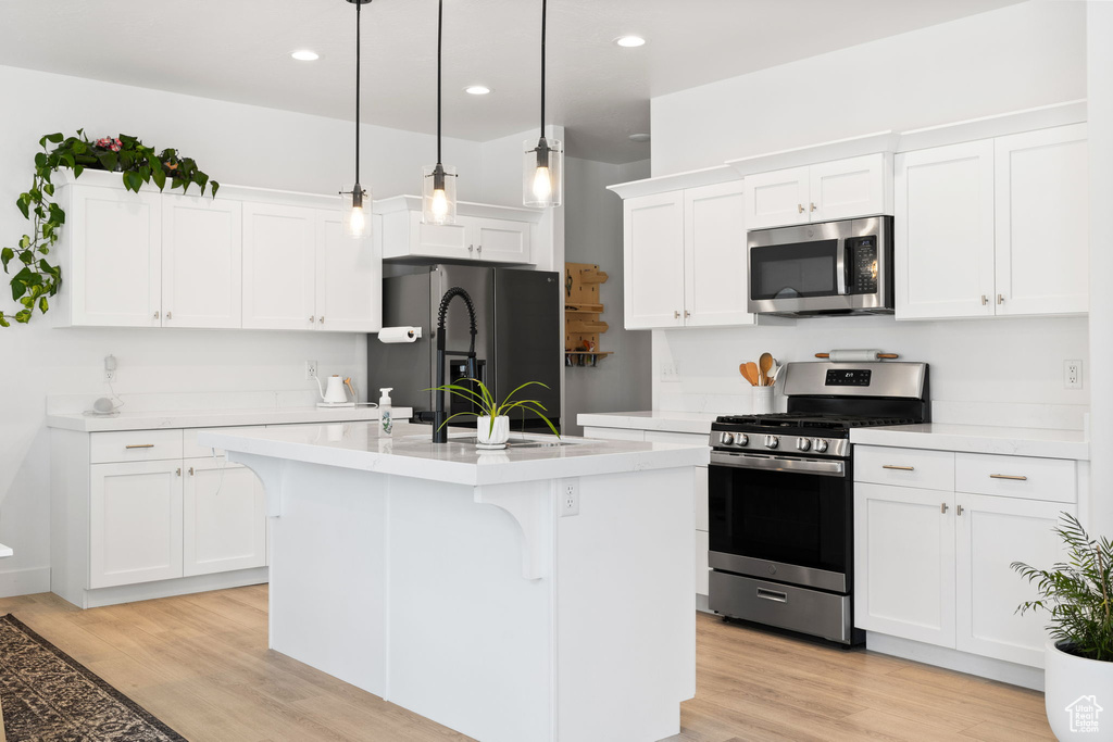 Kitchen featuring appliances with stainless steel finishes, light countertops, light wood finished floors, and recessed lighting