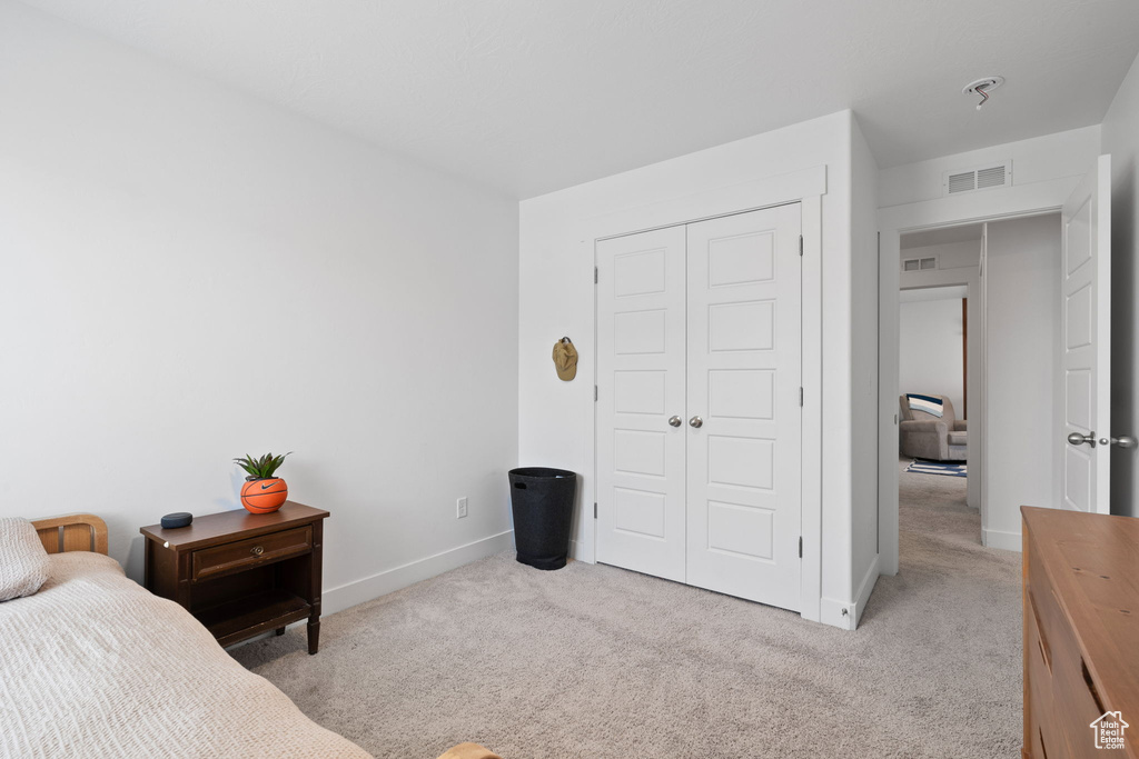 Bedroom featuring light colored carpet and a closet
