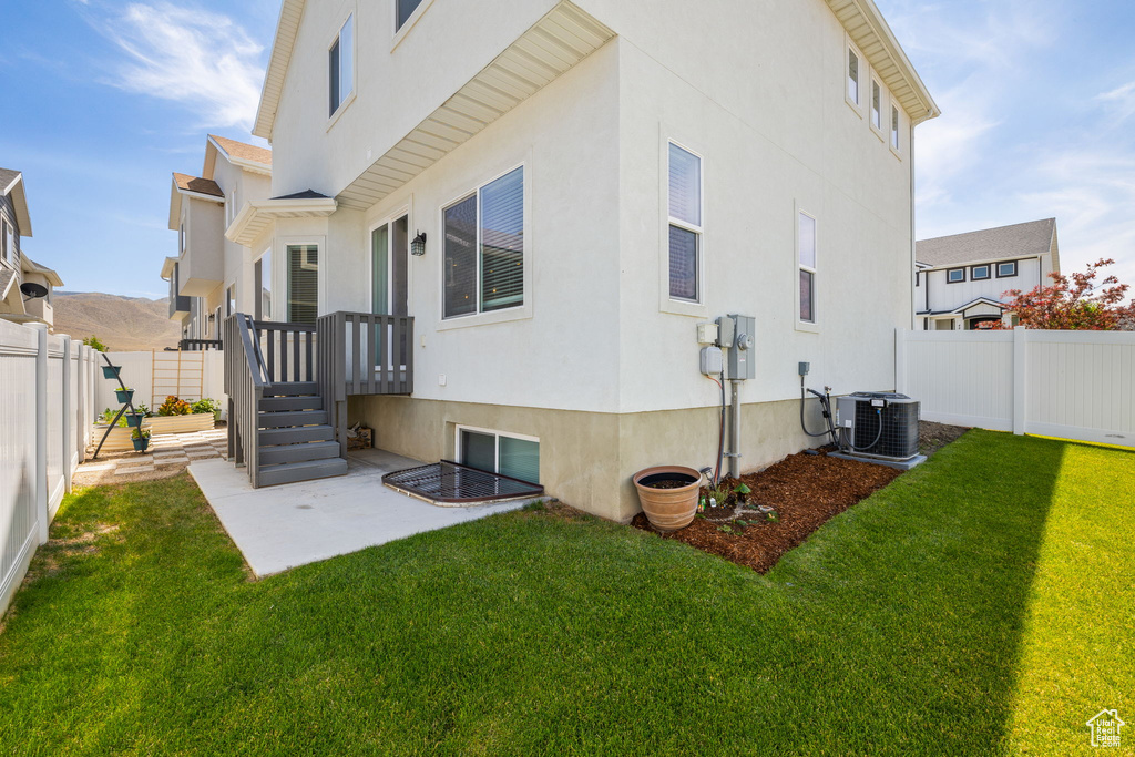 Rear view of house with stucco siding, a fenced backyard, and a patio area