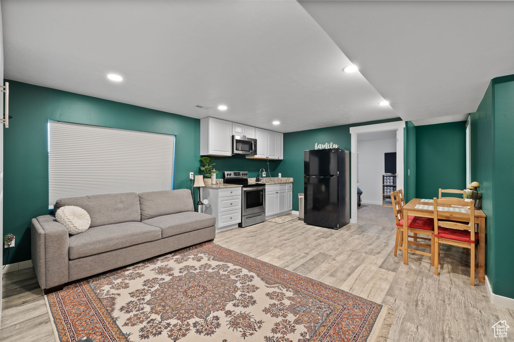 Living room featuring light wood-style flooring, bar area, and recessed lighting