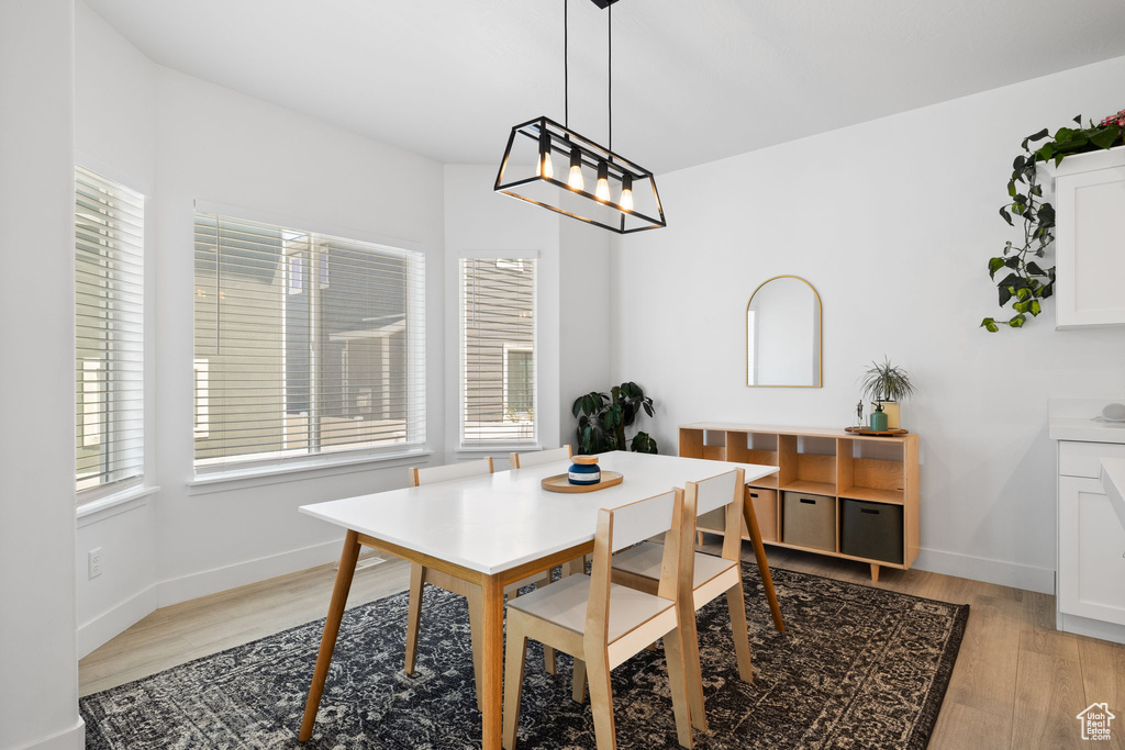 Dining area featuring healthy amount of natural light, light wood finished floors, and a chandelier
