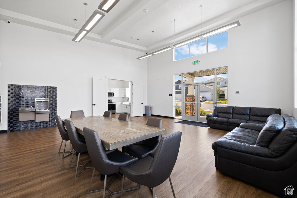 Dining space with a towering ceiling and wood finished floors