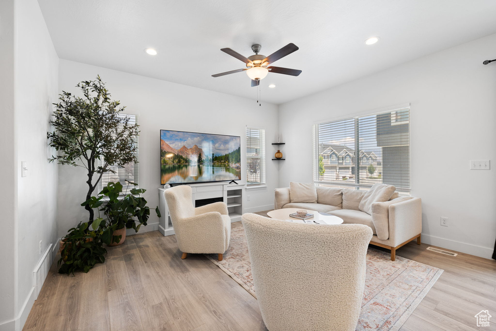 Living room with a ceiling fan, light wood finished floors, and recessed lighting