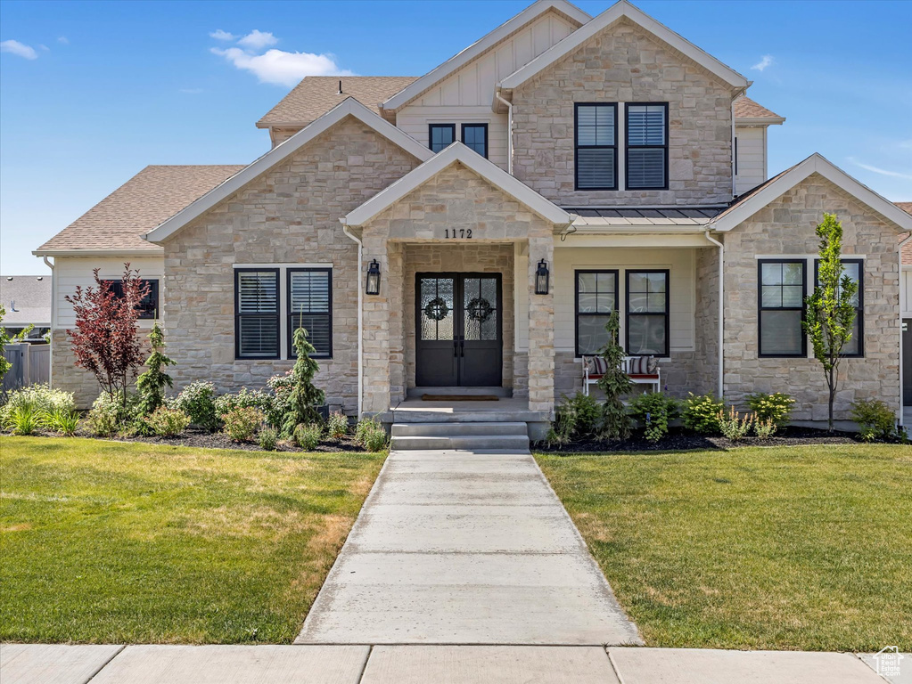 View of front facade with stone siding, a front lawn, and board and batten siding