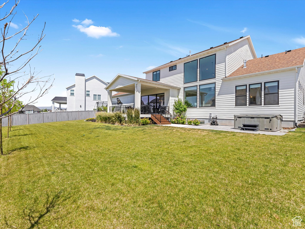 Back of property featuring a hot tub and stairs