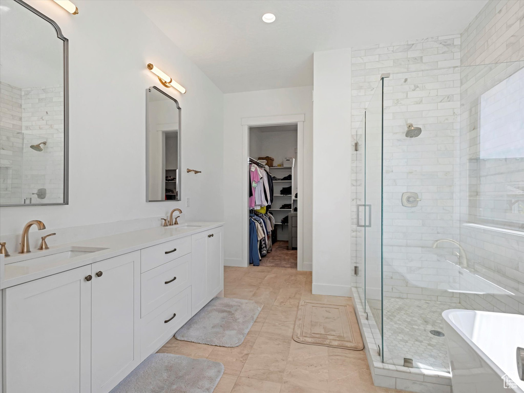 Full bath featuring a stall shower, a soaking tub, double vanity, and a walk in closet