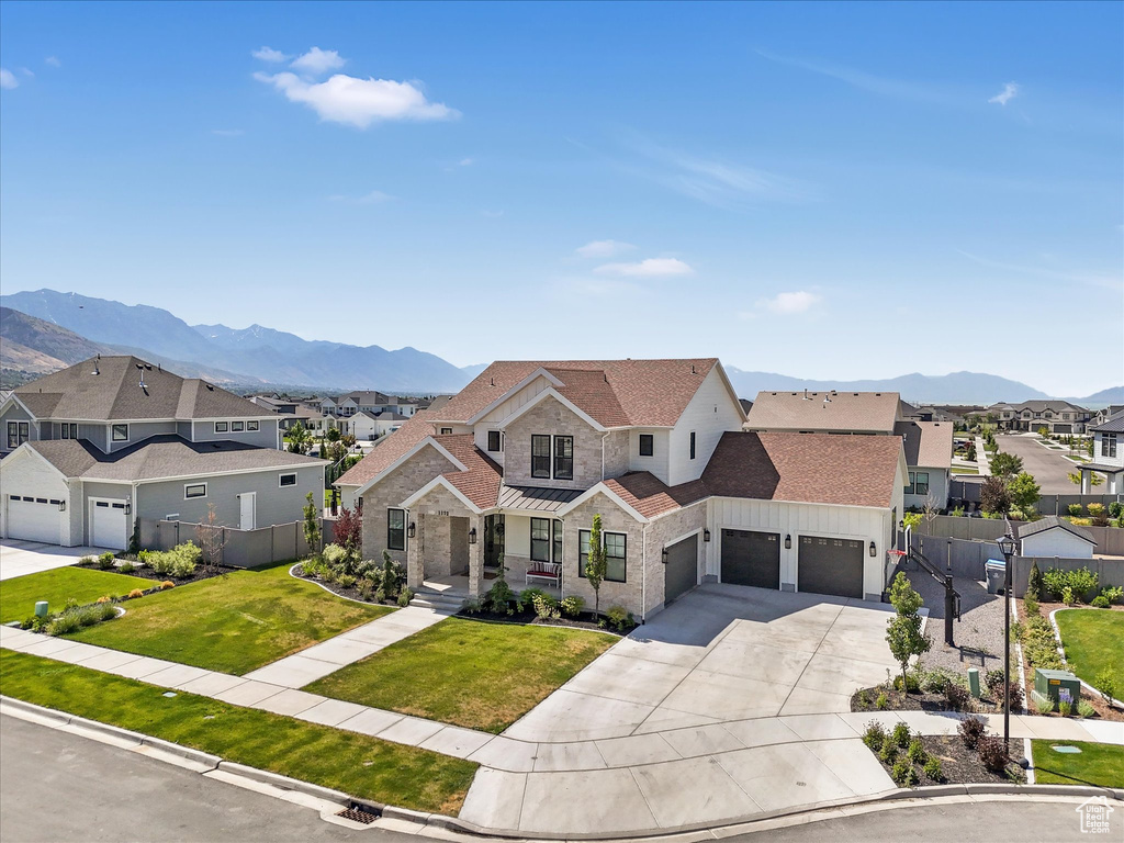 View of front of house featuring an attached garage, a residential view, driveway, and a mountain view