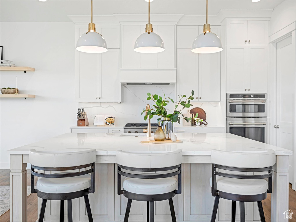 Kitchen with stainless steel double oven, pendant lighting, and white cabinetry