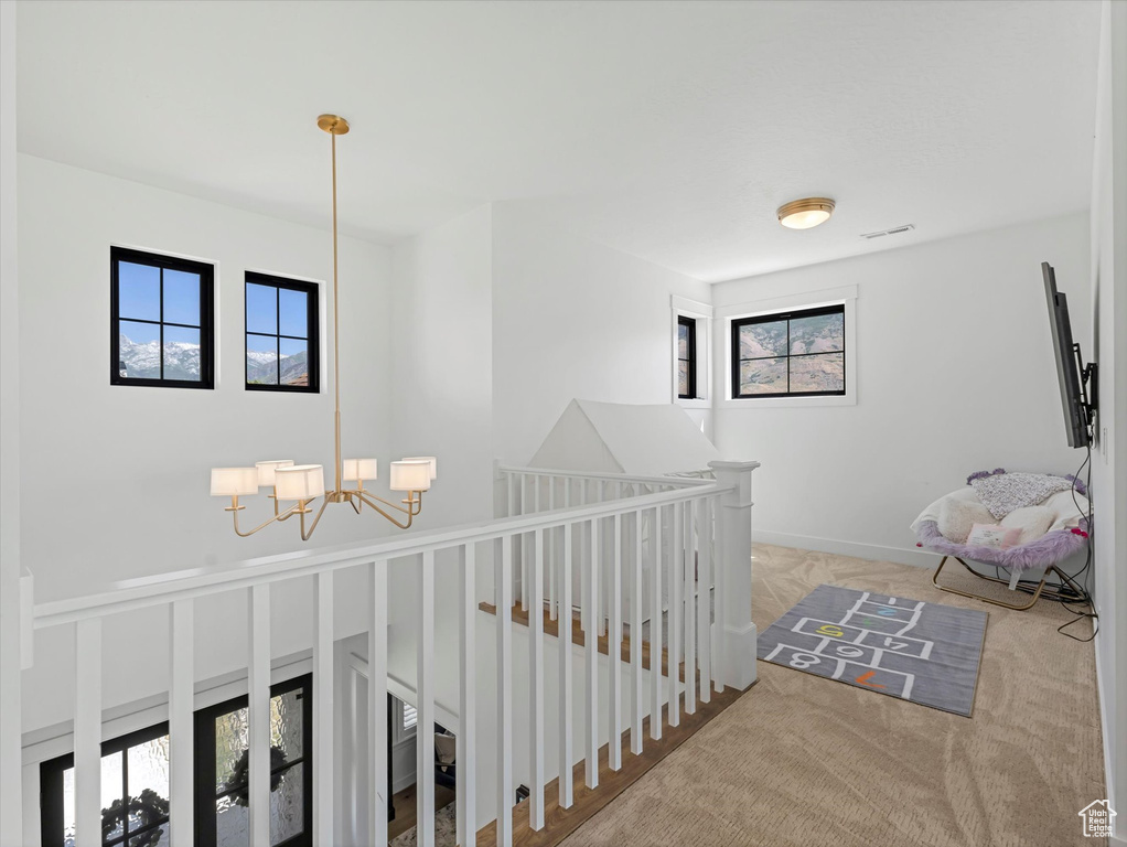 Hallway with a chandelier, an upstairs landing, and carpet floors