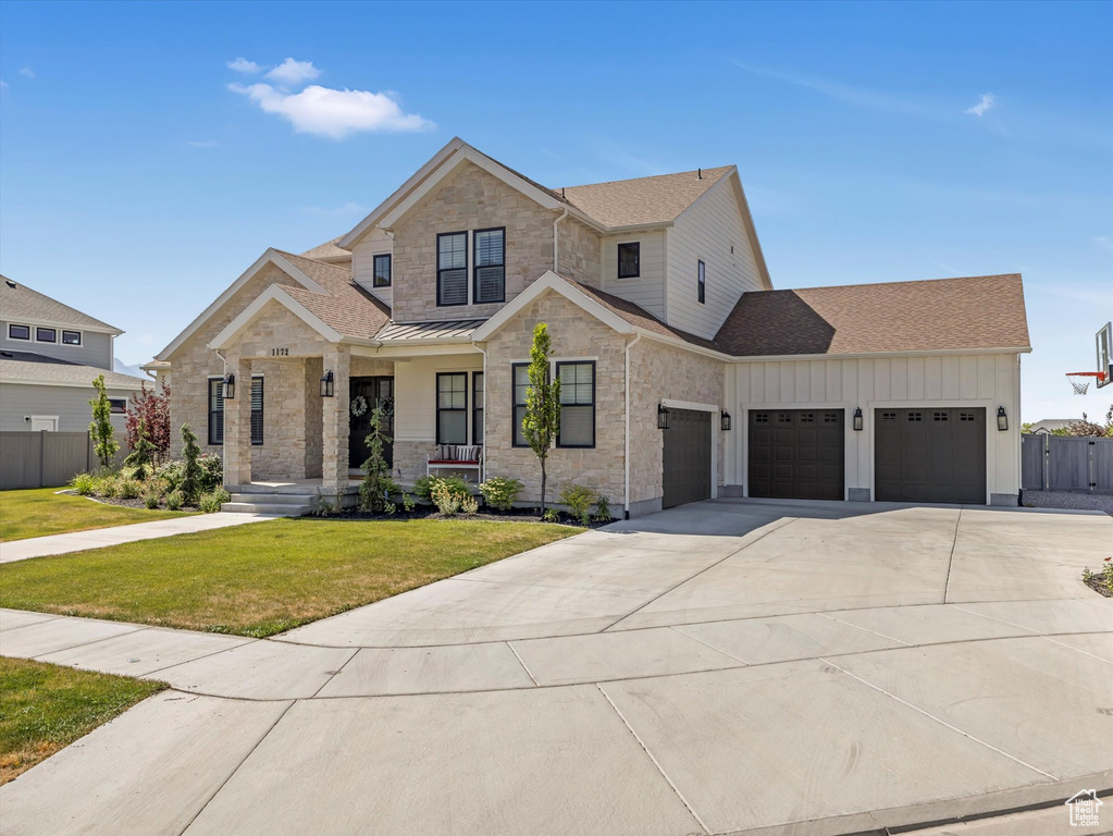 View of front of property featuring a garage, a porch, driveway, a standing seam roof, and roof with shingles