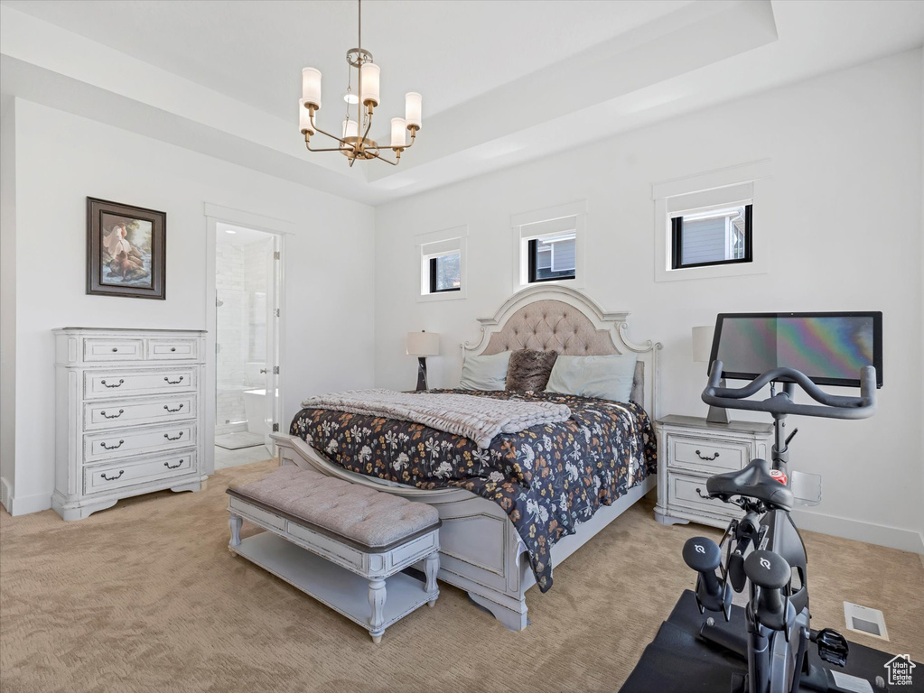 Bedroom with a chandelier, light colored carpet, a tray ceiling, and ensuite bathroom