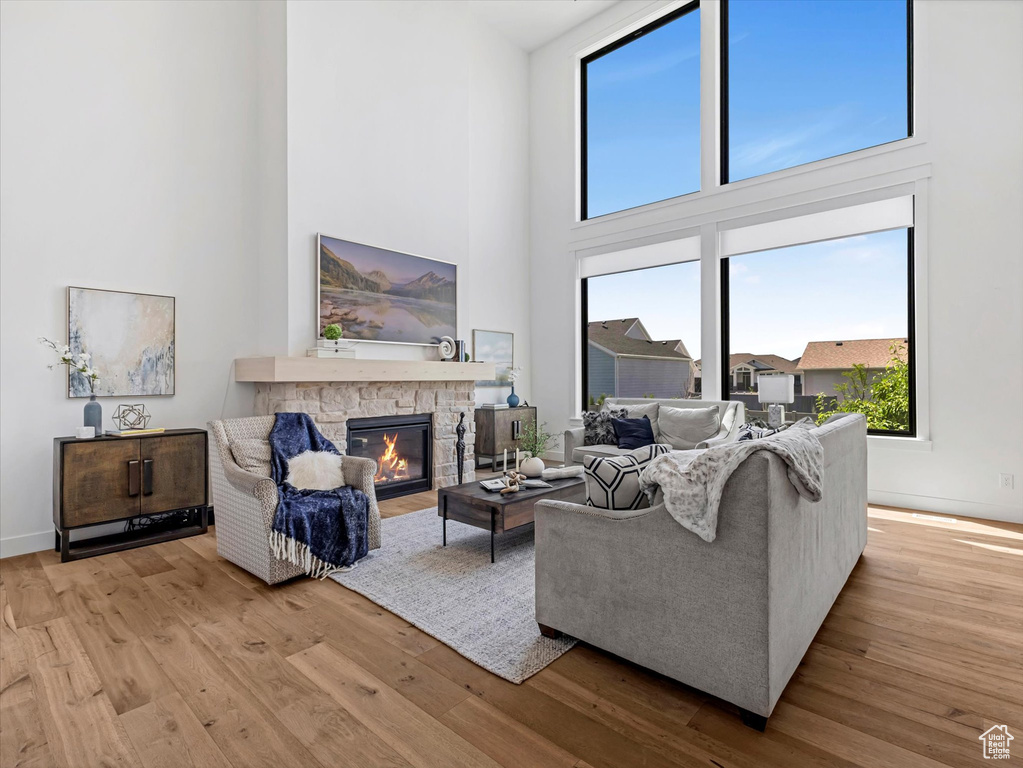 Living area featuring a high ceiling, a stone fireplace, and wood finished floors