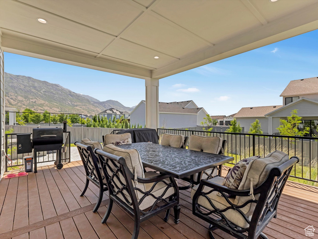 Wooden terrace featuring outdoor dining area, a grill, a mountain view, and a residential view