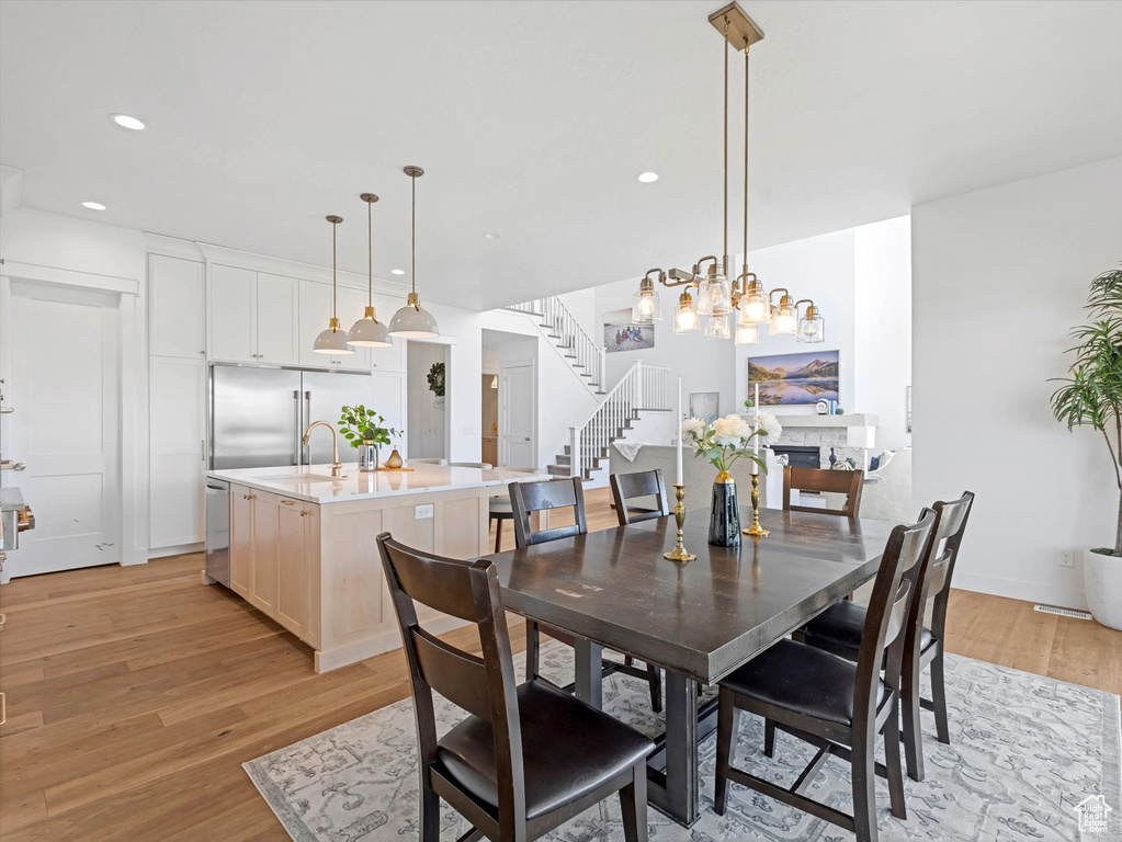 Dining space with light wood-style floors, stairway, recessed lighting, and a chandelier