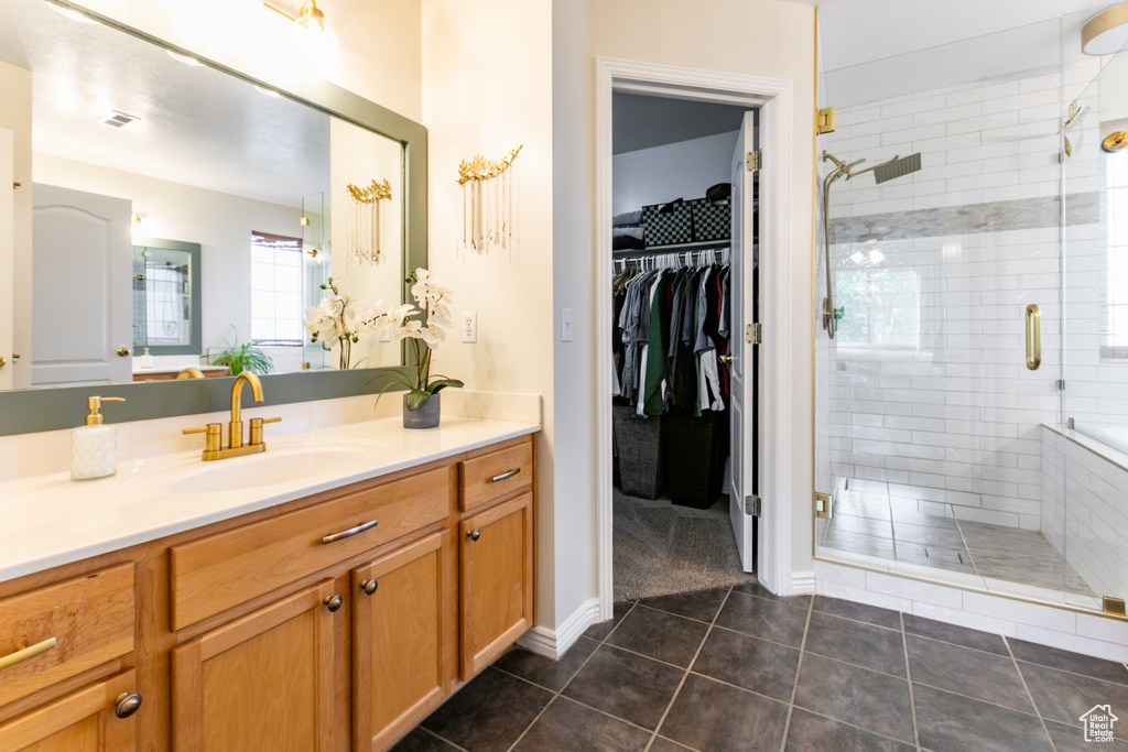 Full bathroom featuring vanity, tile patterned floors, a shower stall, and a walk in closet