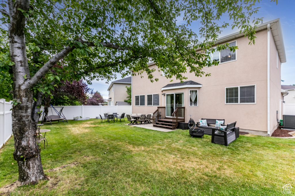 Back of house featuring stucco siding, an outdoor living space with a fire pit, a fenced backyard, and a patio