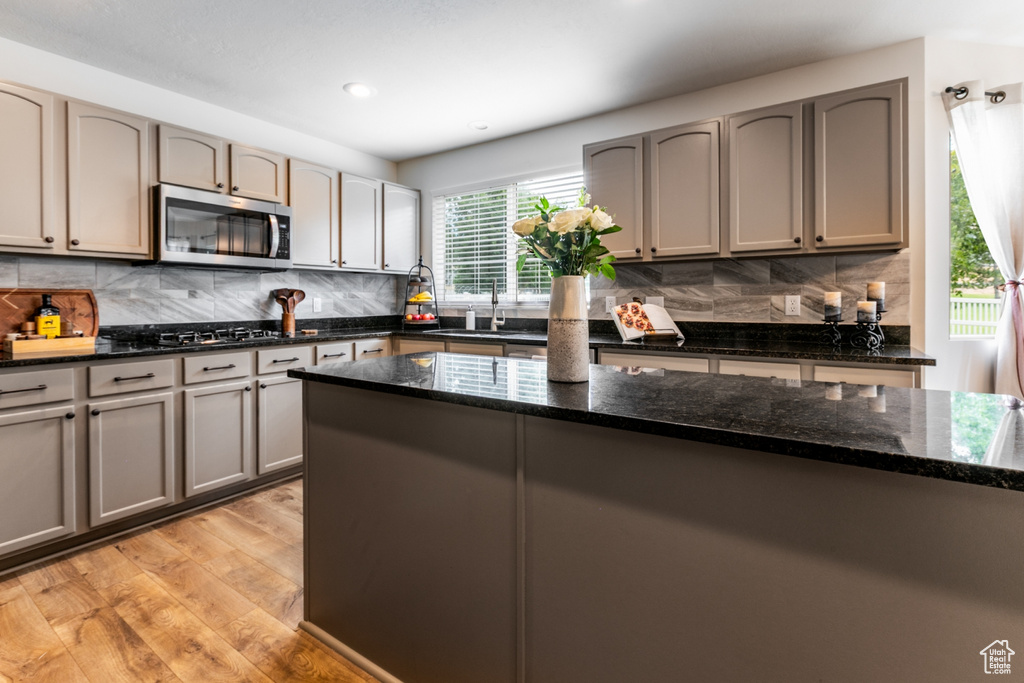 Kitchen featuring stainless steel microwave, light wood-style flooring, tasteful backsplash, gray cabinetry, and recessed lighting