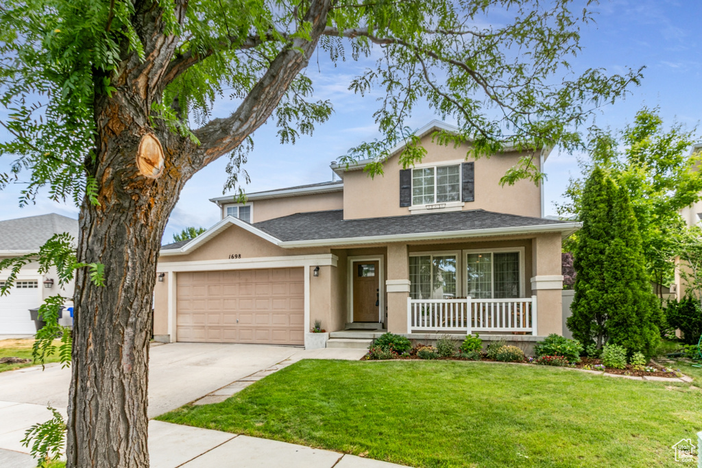 Traditional-style house with stucco siding, an attached garage, driveway, and a porch
