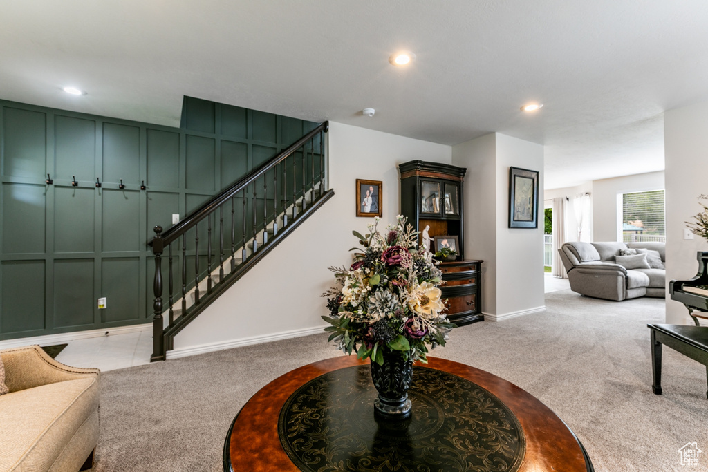 Carpeted living area with stairs and recessed lighting
