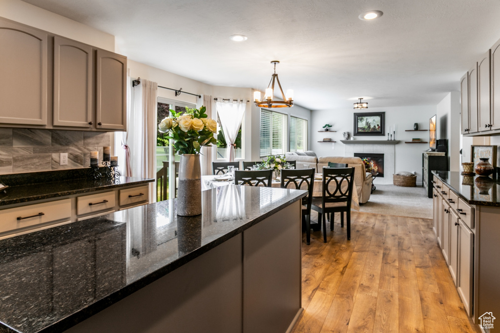 Kitchen with a lit fireplace, tasteful backsplash, recessed lighting, dark stone countertops, and open floor plan