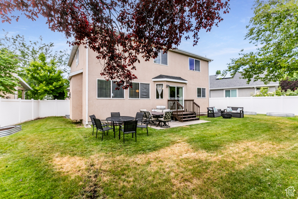 Rear view of house featuring stucco siding, a fenced backyard, a patio, and outdoor lounge area