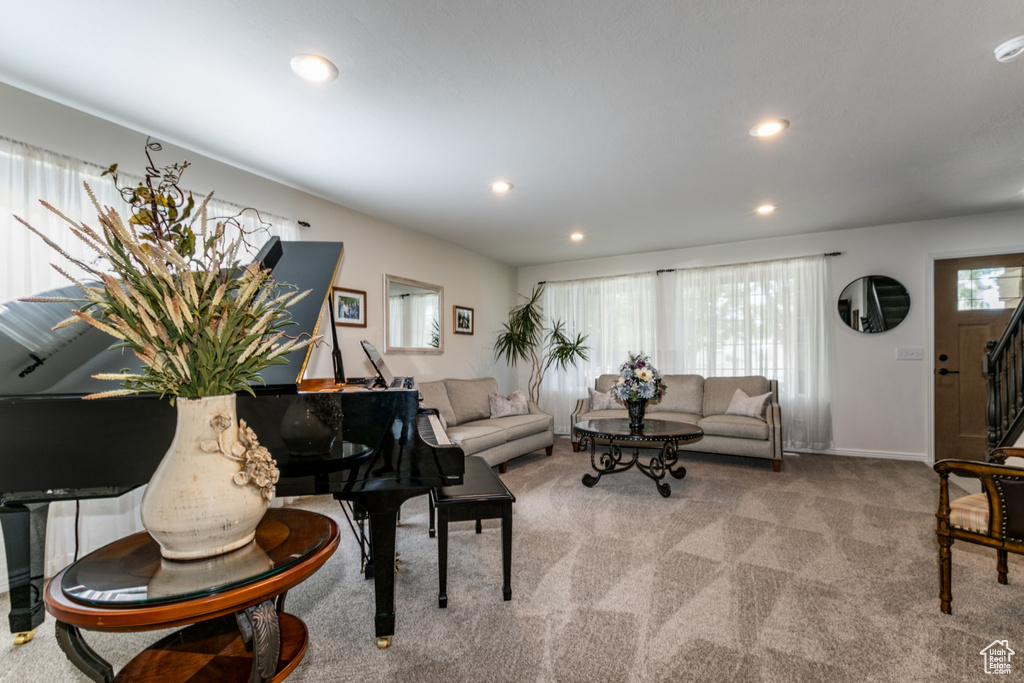 Carpeted living area with recessed lighting and stairway