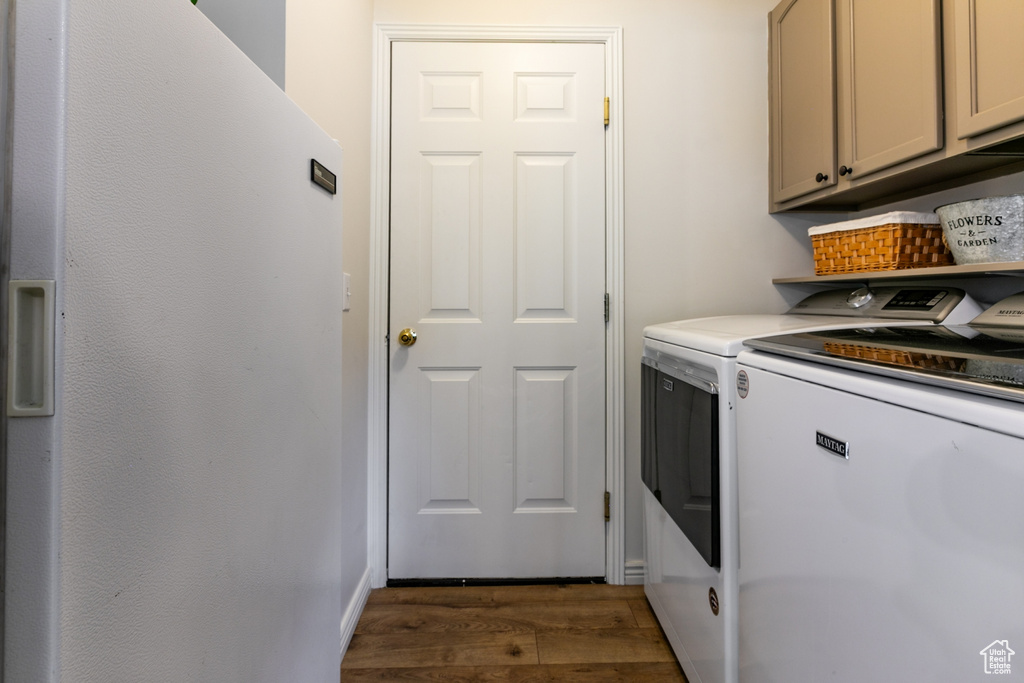 Washroom with independent washer and dryer, dark wood finished floors, and cabinet space