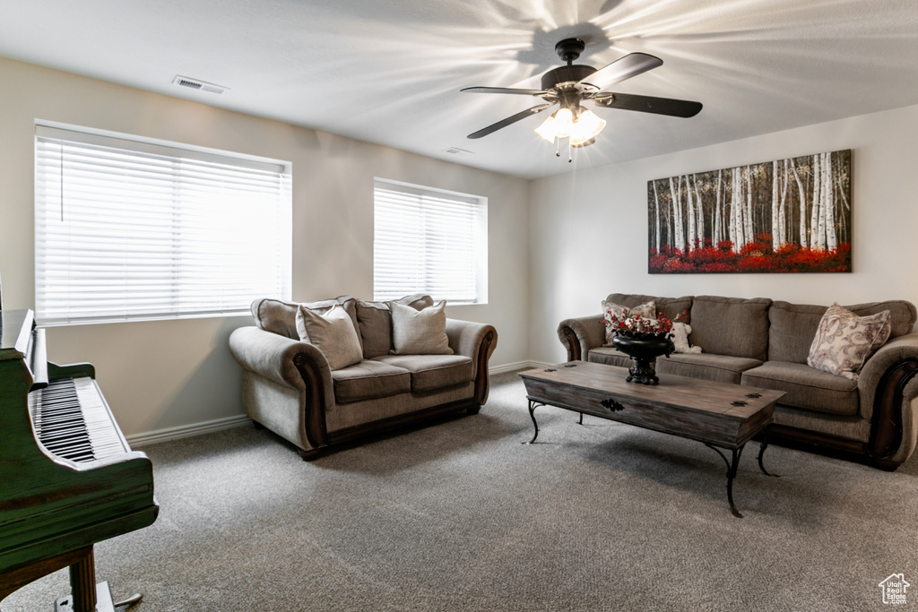 Carpeted living room with baseboards and a ceiling fan