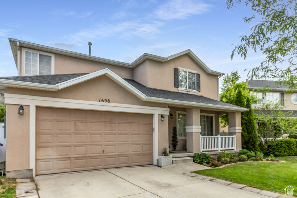 View of front of property featuring a porch, stucco siding, concrete driveway, a garage, and a front lawn