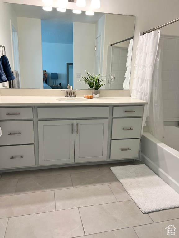 Ensuite bathroom featuring vanity, shower / bathtub combination with curtain, and tile patterned flooring
