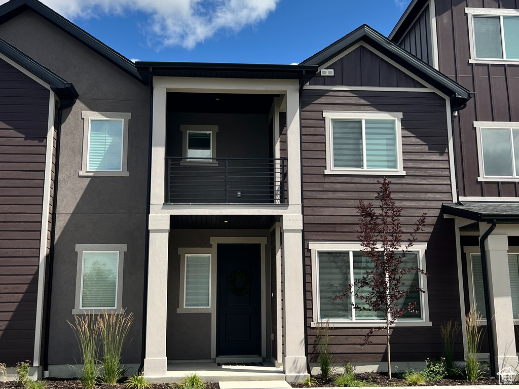 View of front of property with a balcony, a front lawn, and board and batten siding