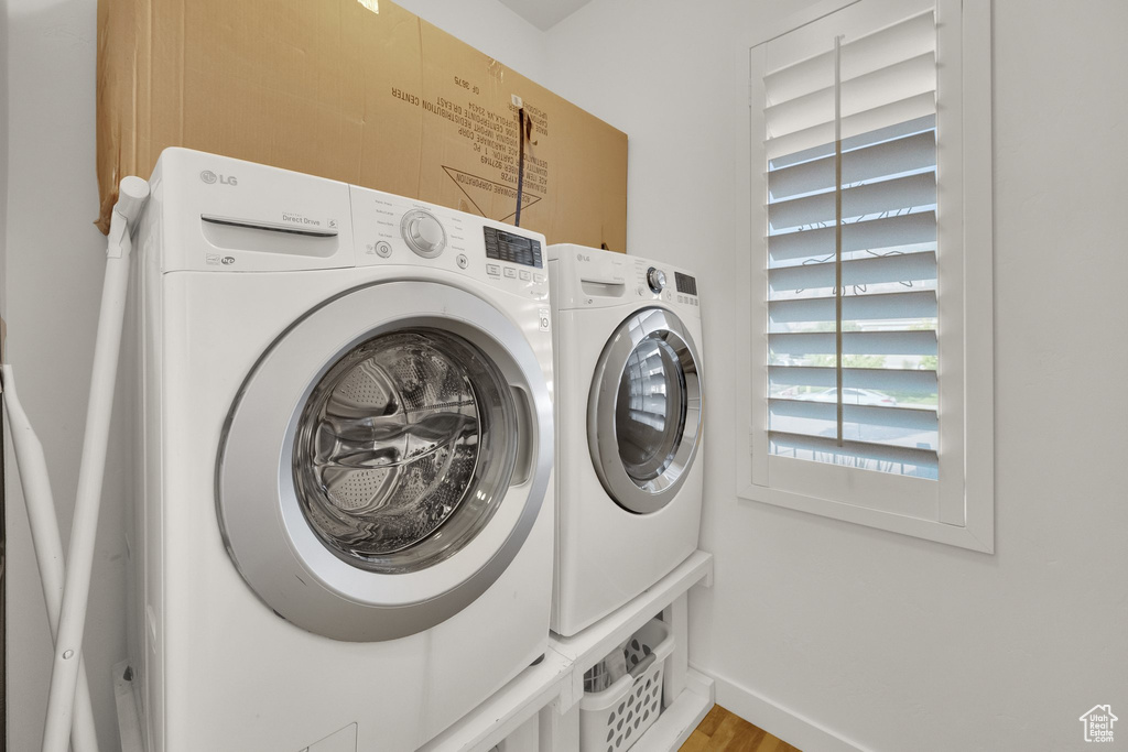 Washroom with washing machine and dryer and light wood-type flooring