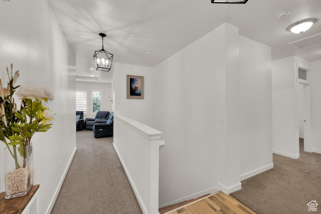 Hall featuring an upstairs landing and light colored carpet