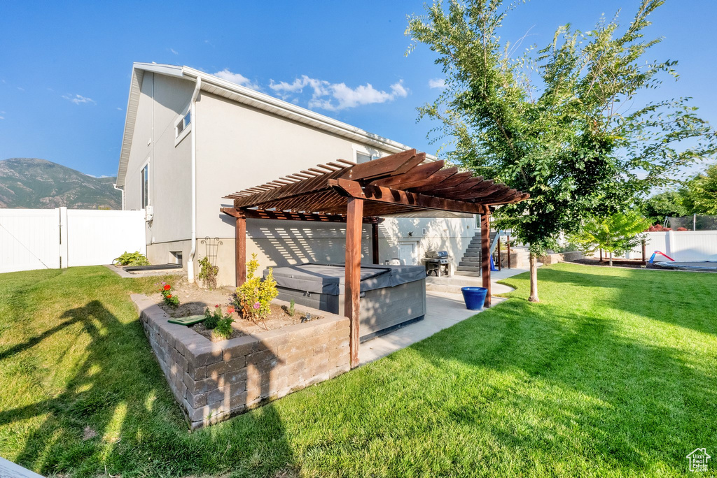 Rear view of property with a fenced backyard, a pergola, stucco siding, a patio area, and a mountain view