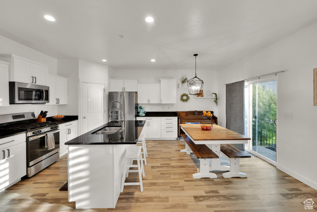 Kitchen with stainless steel appliances, light wood-style floors, dark countertops, recessed lighting, and white cabinets
