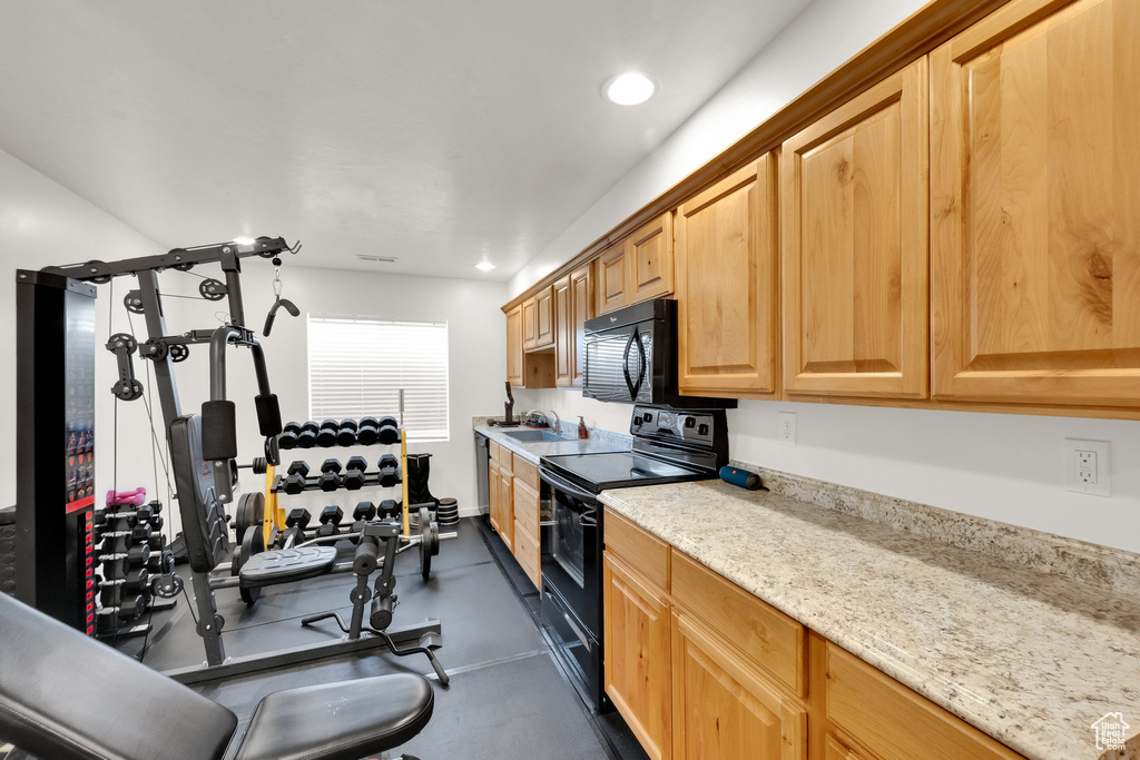 Kitchen with black appliances, recessed lighting, and light stone countertops
