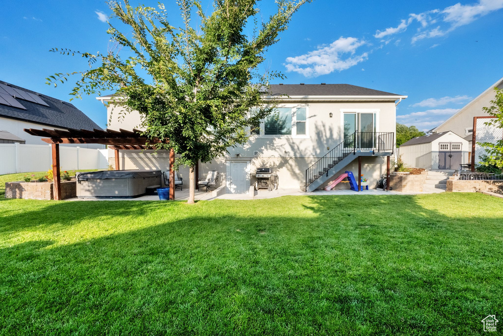 Rear view of house with a hot tub, a patio area, stairs, stucco siding, and a pergola