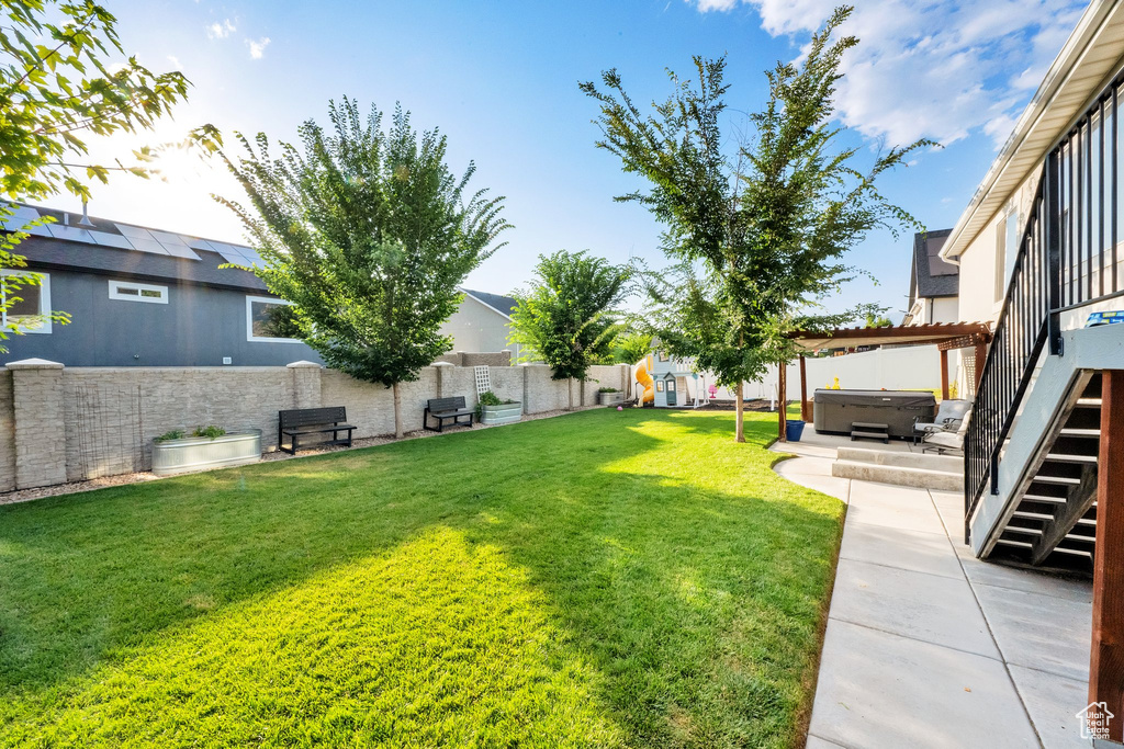 Fenced backyard featuring a hot tub, stairs, and a patio