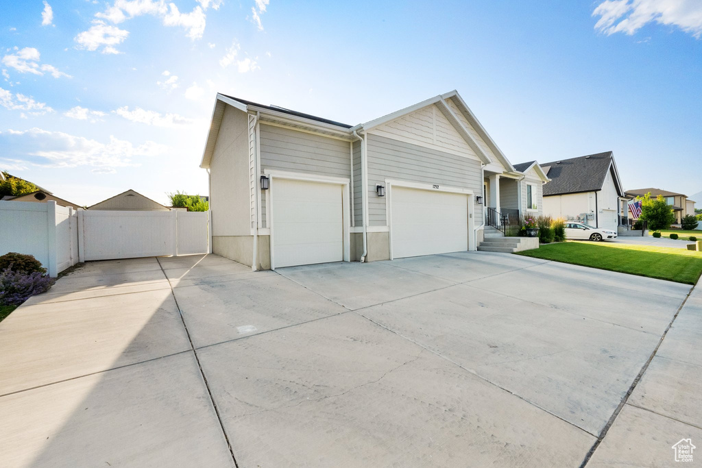View of side of home with concrete driveway, an attached garage, and a residential view