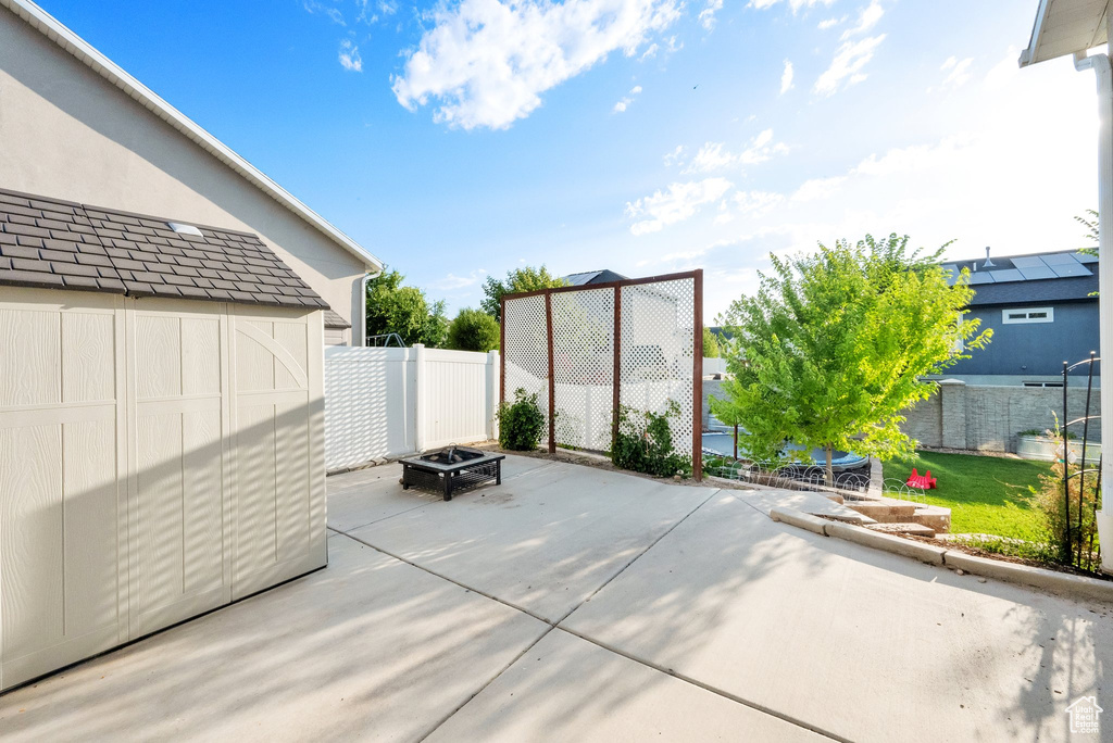 View of patio with a fire pit and a storage unit