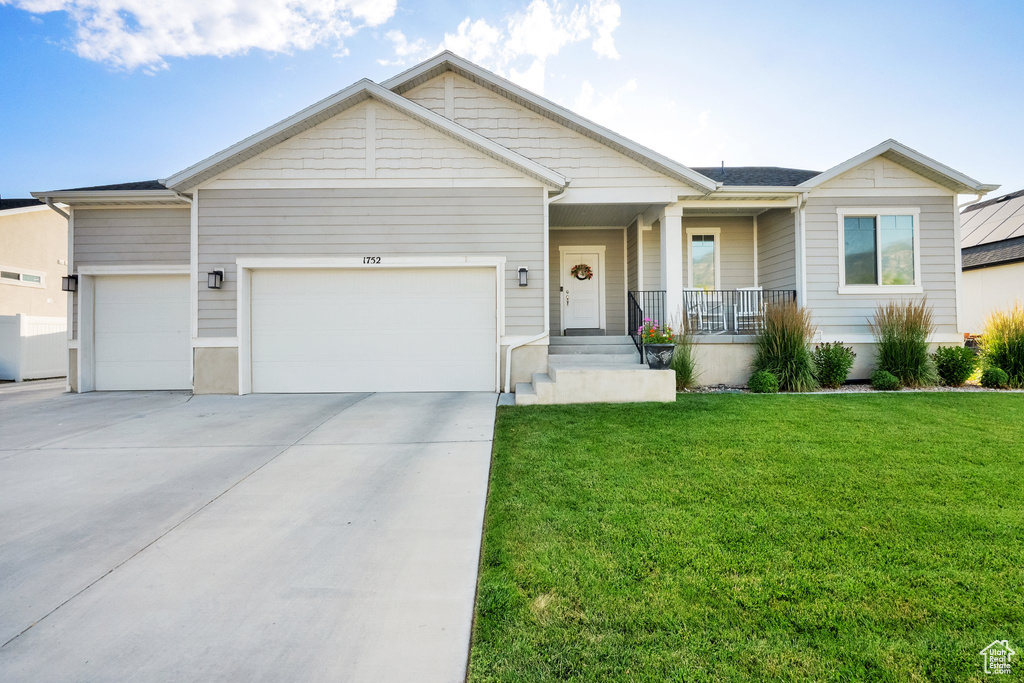 View of front of property featuring a porch, an attached garage, a front yard, and concrete driveway